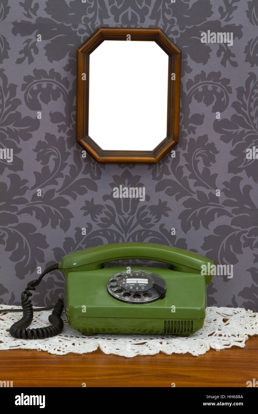 Old fashioned telephone and wooden frame on decorative wallpaper Stock Photo