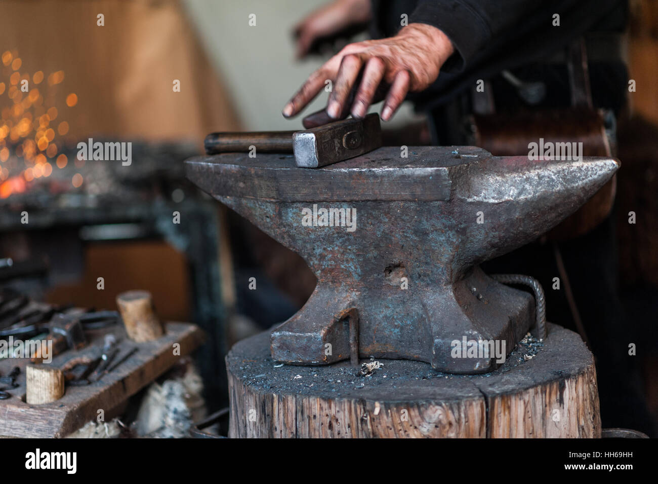 Blacksmith at the workshop. Working metal with hammer and tools on the ...