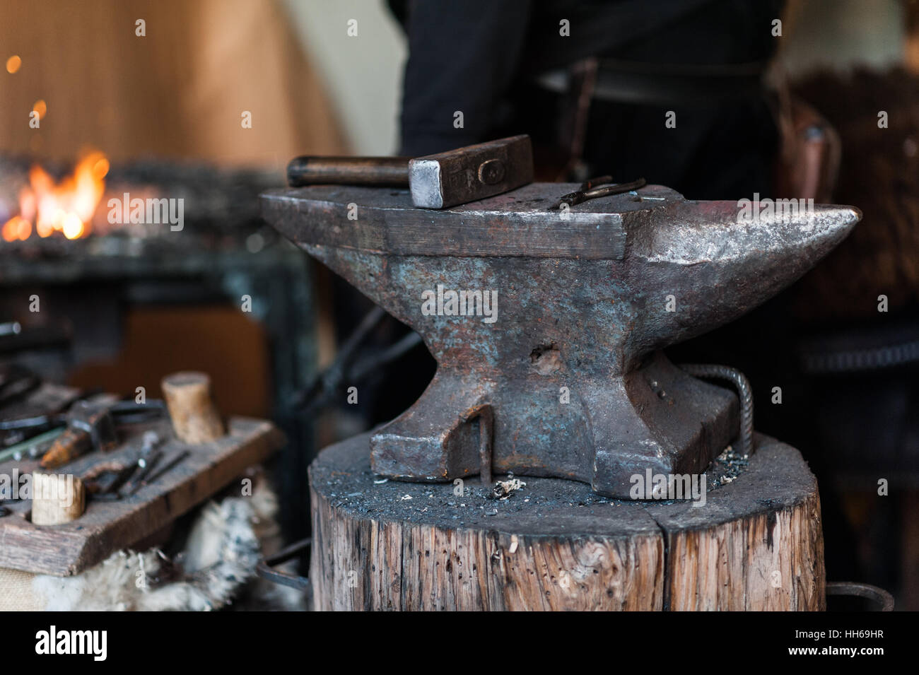 Blacksmith at the workshop. Working metal with hammer and tools on the anvil in the forge. Stock Photo