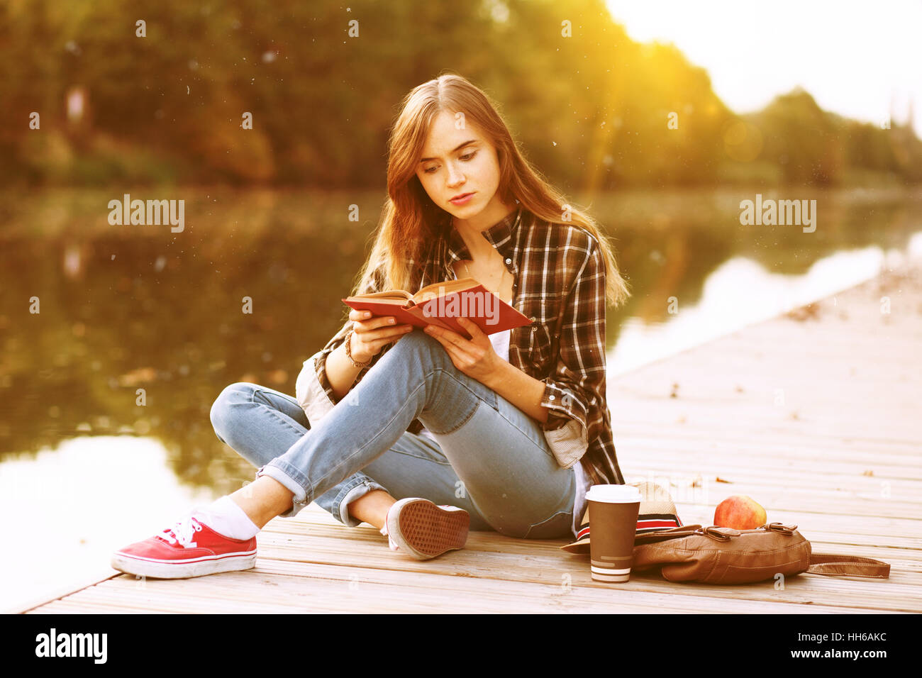 Young beautiful girl sitting on pier Stock Photo