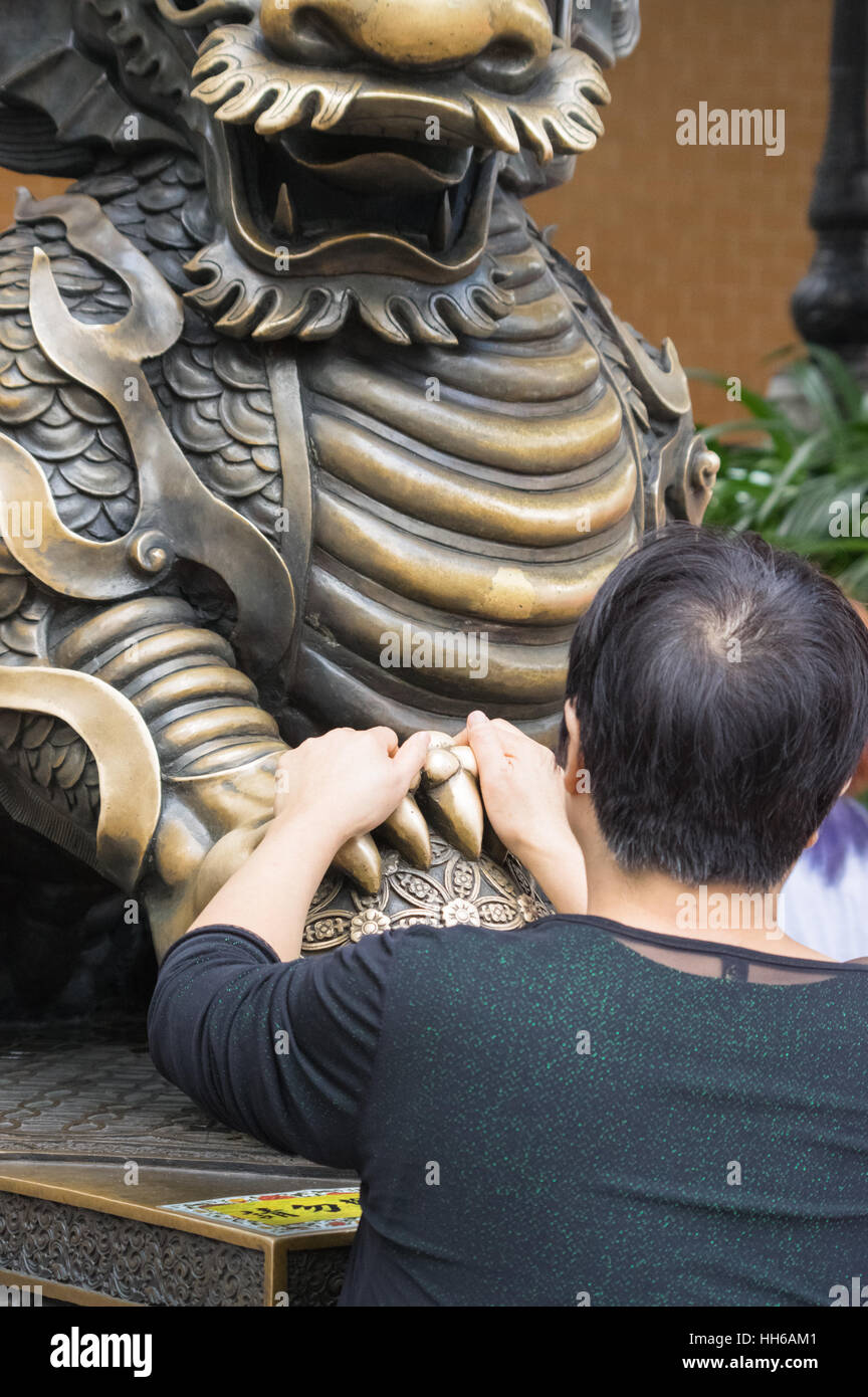 Woman with brass dragon at Sik Sik Yuen Wong Tai Sin Temple, Hong Kong Stock Photo