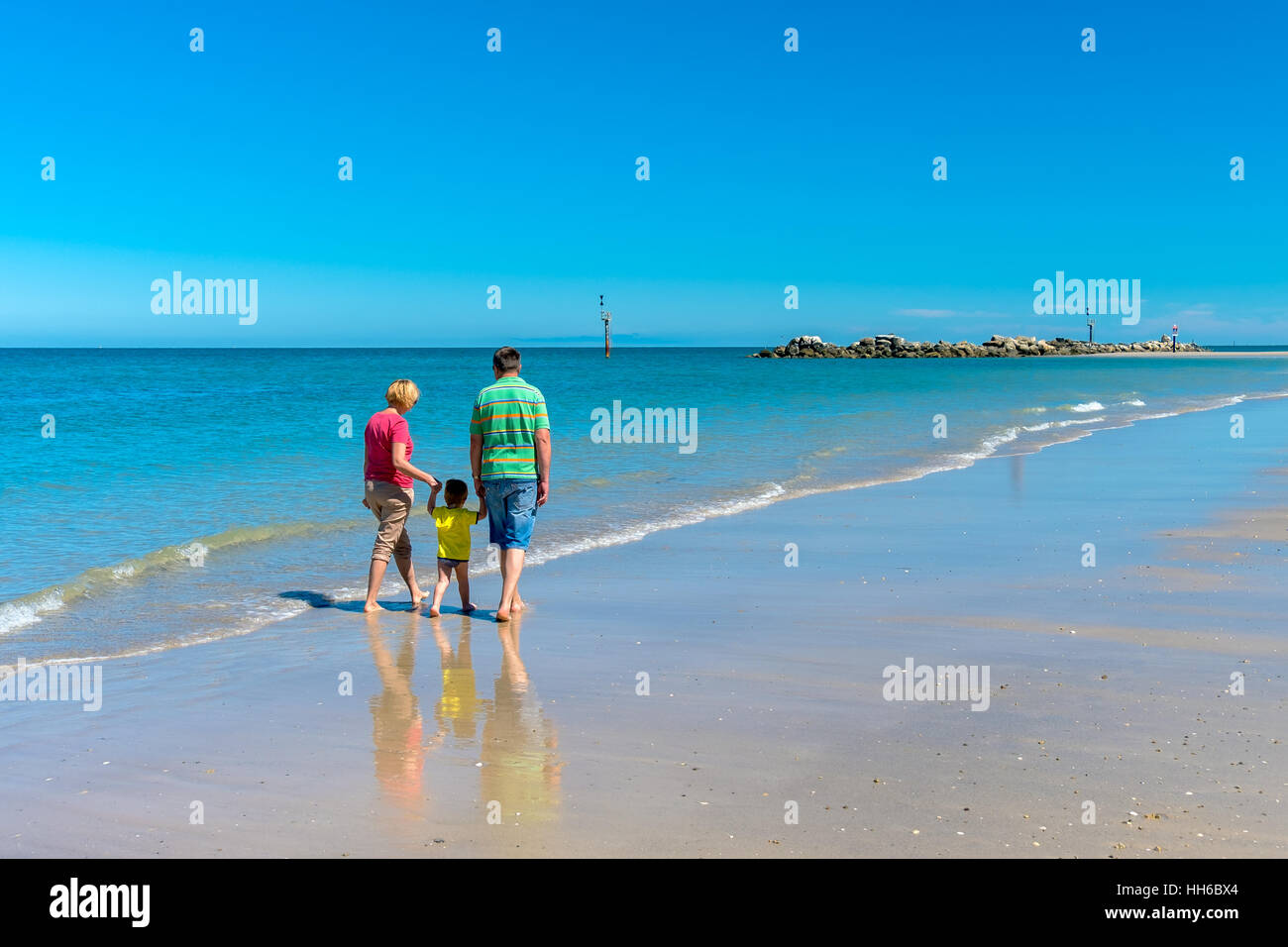 Grandfather and grandmother with grandson dreaming and holding hands of each other on the beach. Stock Photo