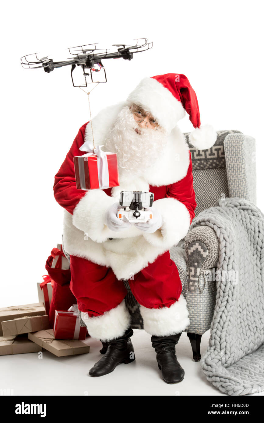 Santa Claus, sitting on grey armchair, using hexacopter drone Stock Photo