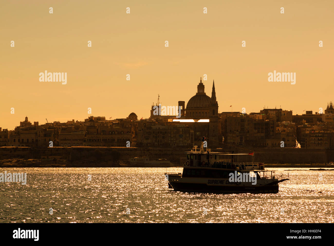 Sunset silhouette Sliema Creek with Floriana Basilica of Our Lady of Mount Carmel and St Pauls co-cathedral.  Valletta in the background Stock Photo