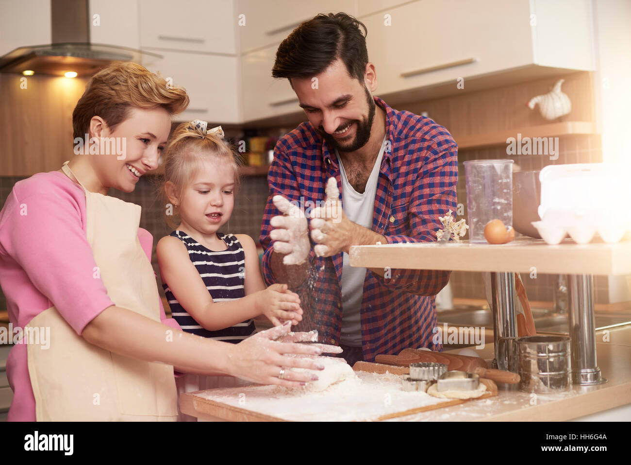 Little girl spending time with parents in the kitchen Stock Photo