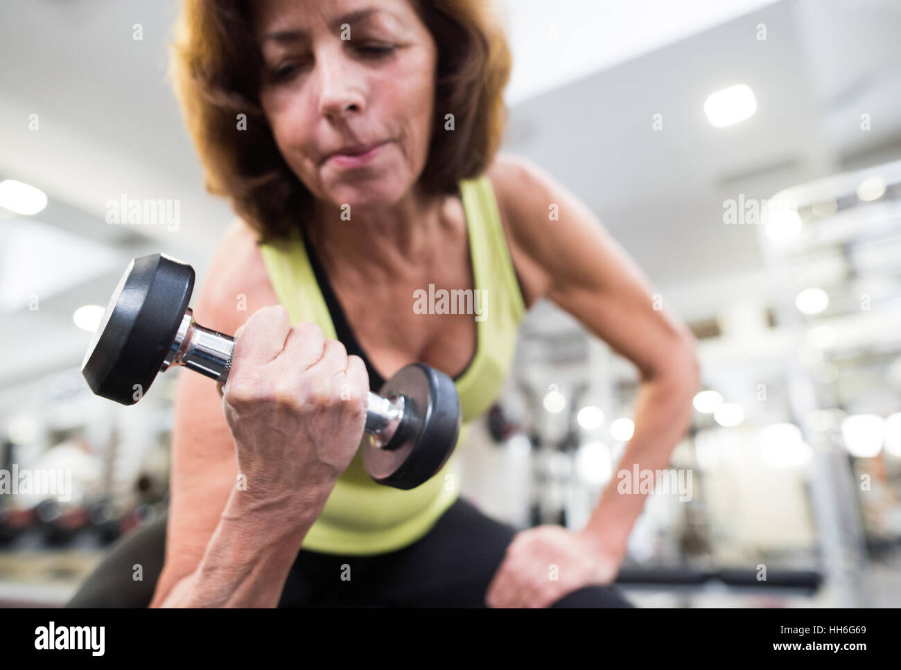 Senior woman in gym working out with weights Stock Photo - Alamy