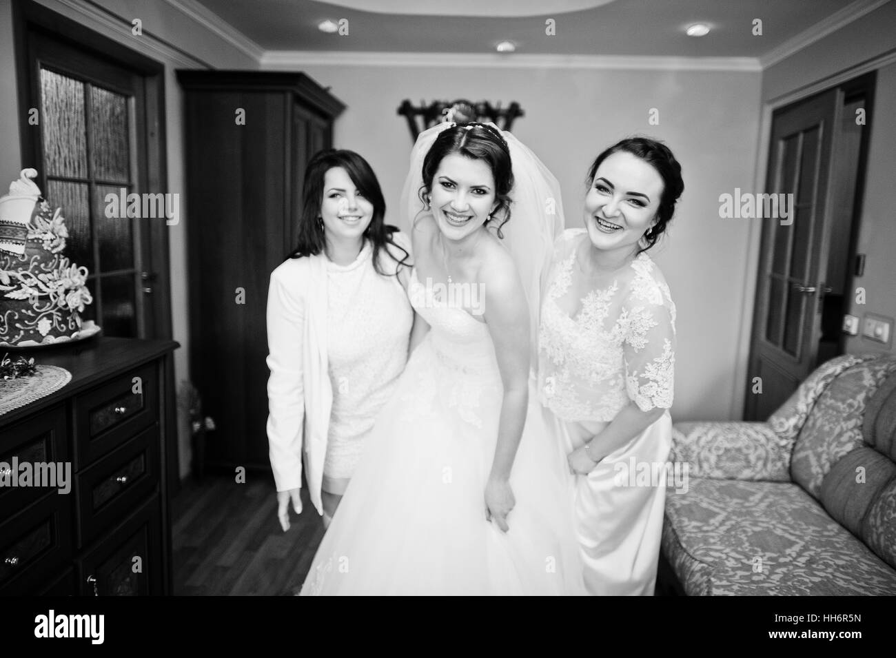 Elegance brunette bride with bridesmaids posed at her room on wedding morning day. Black and white photo Stock Photo