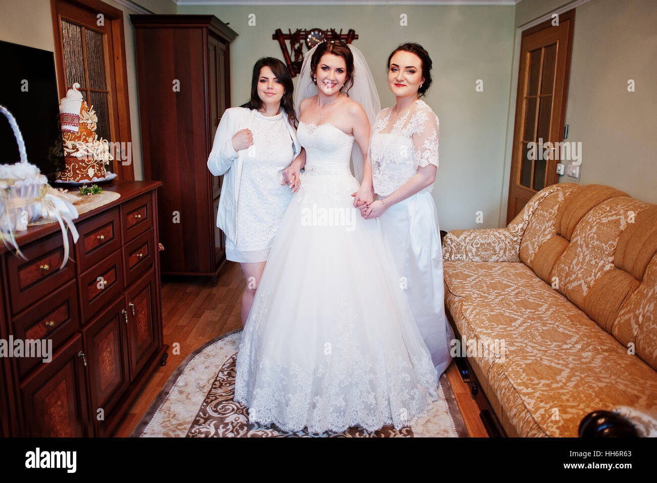 Elegance brunette bride with bridesmaids posed at her room on wedding morning day. Stock Photo