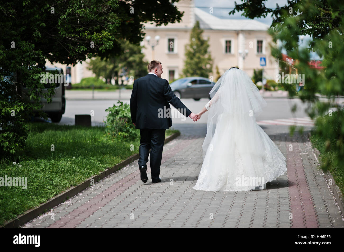 Happy wedding couple walking holding hands and smiling Stock Photo - Alamy