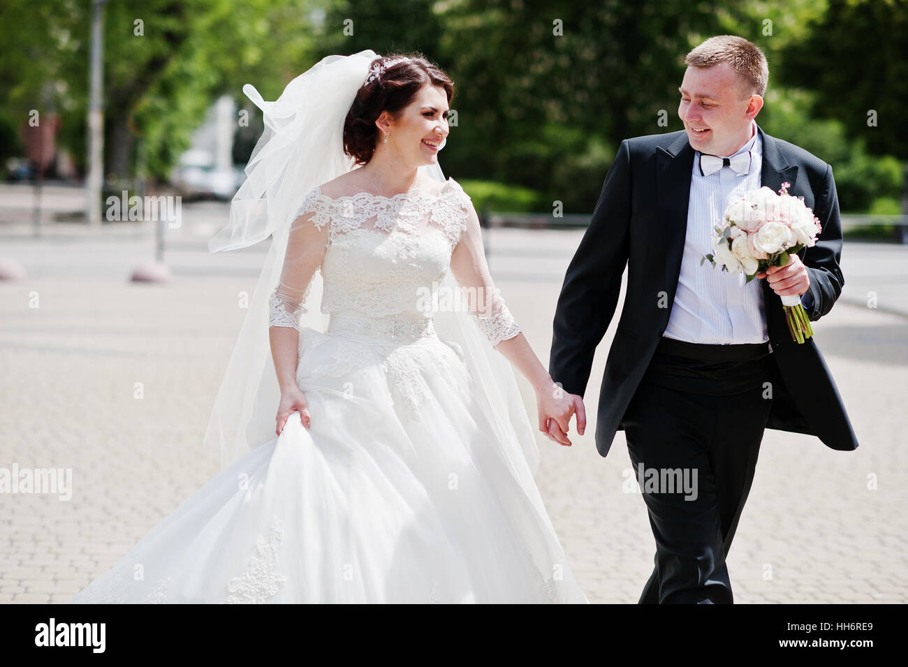 Happy wedding couple walking holding hands and smiling Stock Photo - Alamy