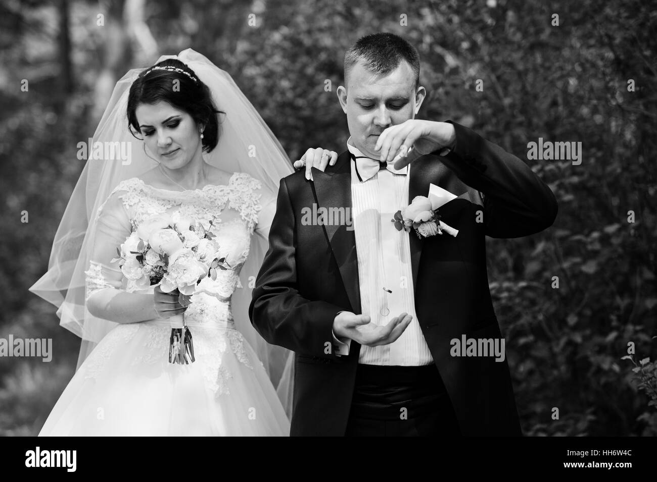 Wedding couple stay at forest. Groom throw rings on air. Black and