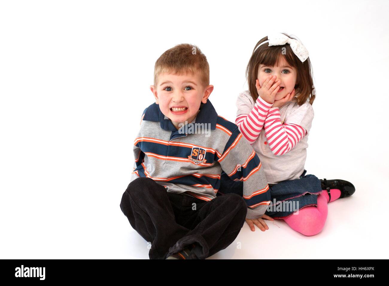Brother and sister children kids laughing playing and having fun together shock surprise excitement siblings girl boy twins hand over face concept Stock Photo