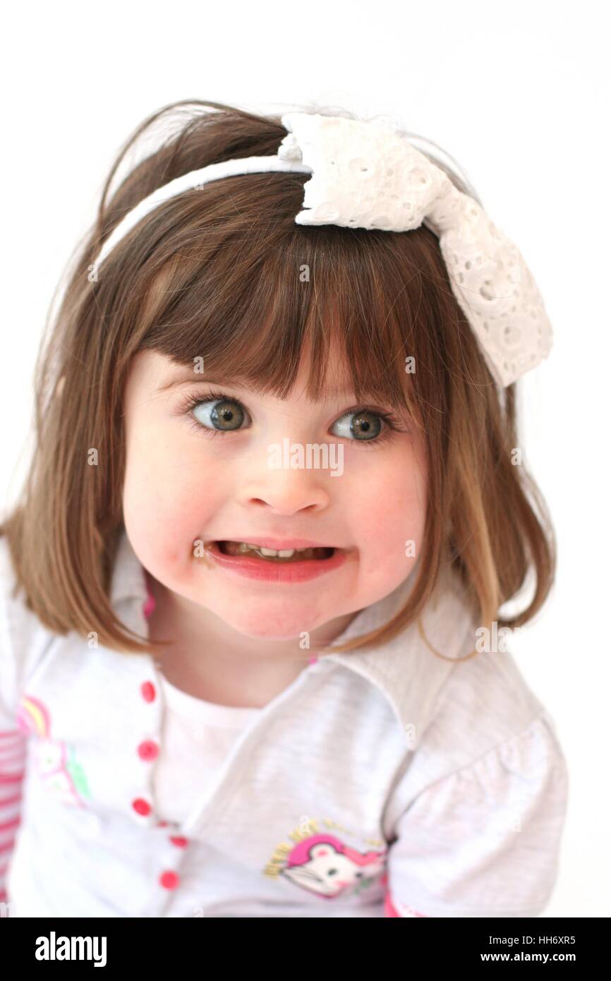 Little girl, three year old child making a funny angry face, grinding / clenching her teeth kids faces, grimacing, innocent concept fringe bob Stock Photo