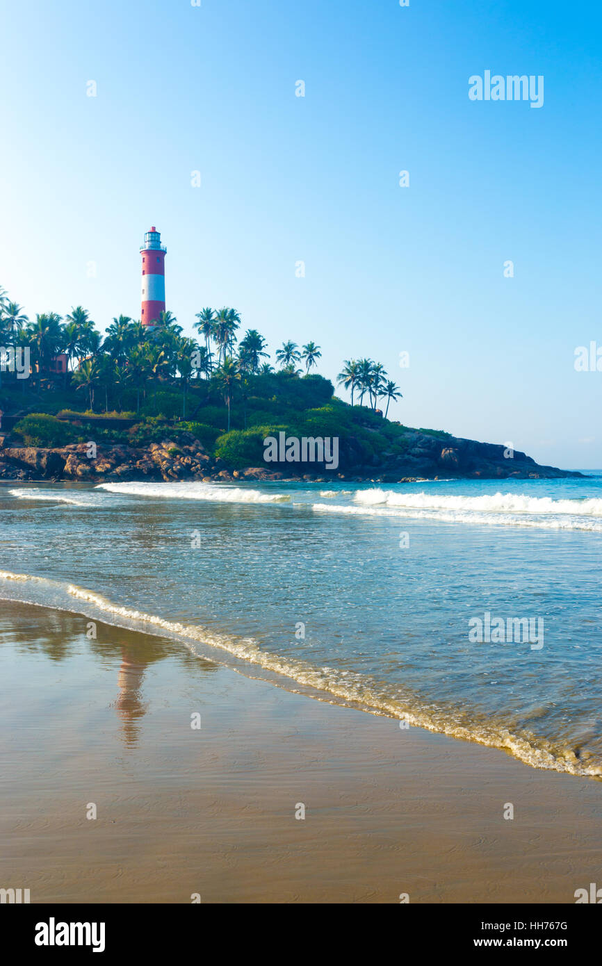 Lighthouse standing above the rocky outcrop above the ocean waves at Kovalam Beach in Kerala, India. Vertical Stock Photo