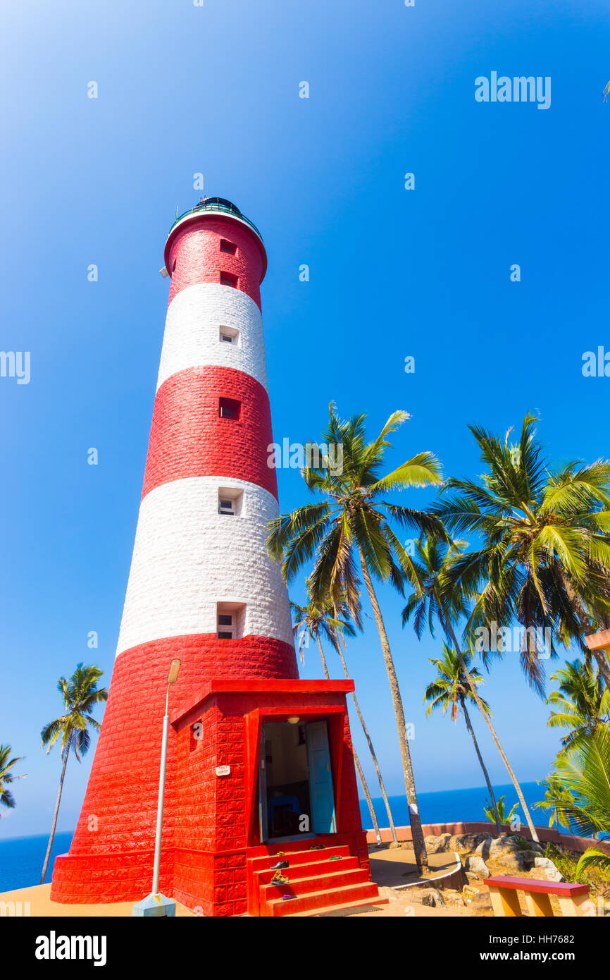 Ocean and horizon seen behind red and white striped lighthouse at Kovalem Beach, Kerala, India on a clear, blue sky day Stock Photo