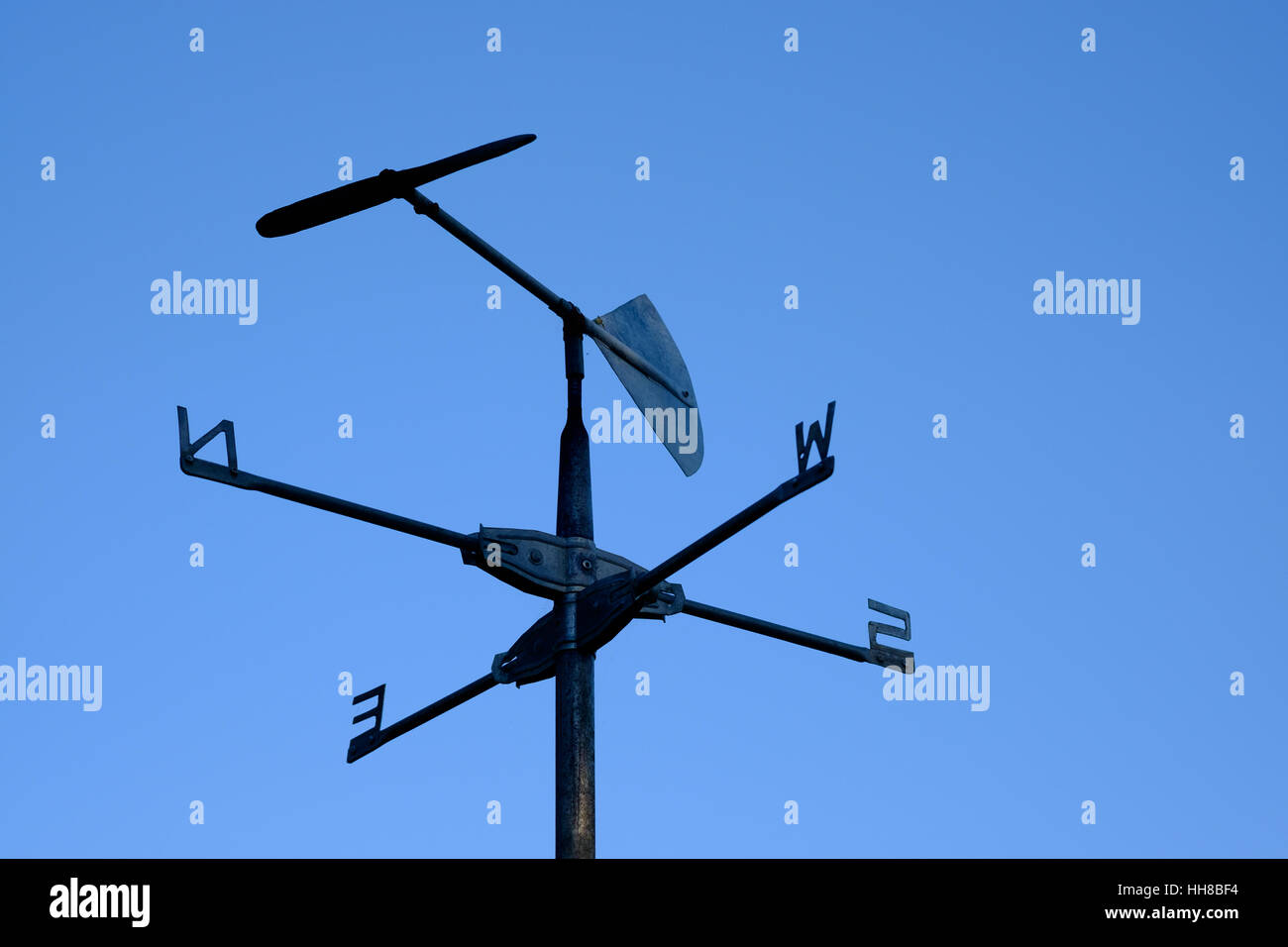 Rustic weather vane, partial silhouette, against a clear blue sky, showing  wind direction of north by north west Stock Photo - Alamy