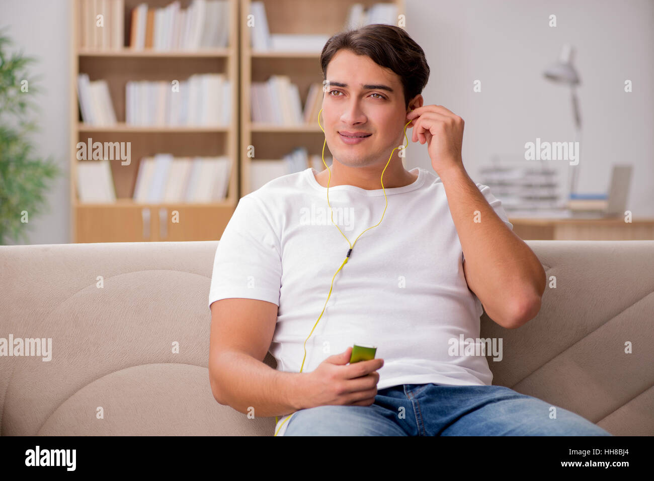Man listening music sitting in couch Stock Photo - Alamy