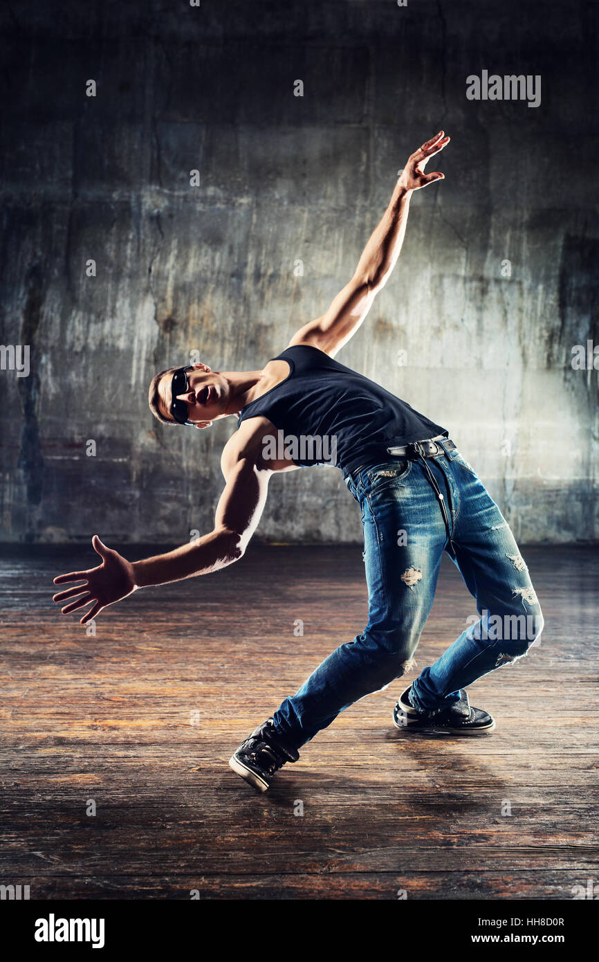 Young man break dancer standing in dodge bullets pose on old wall