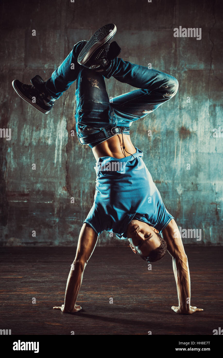 Young man break dancing on old wall background. Vintage film style colors. Stock Photo