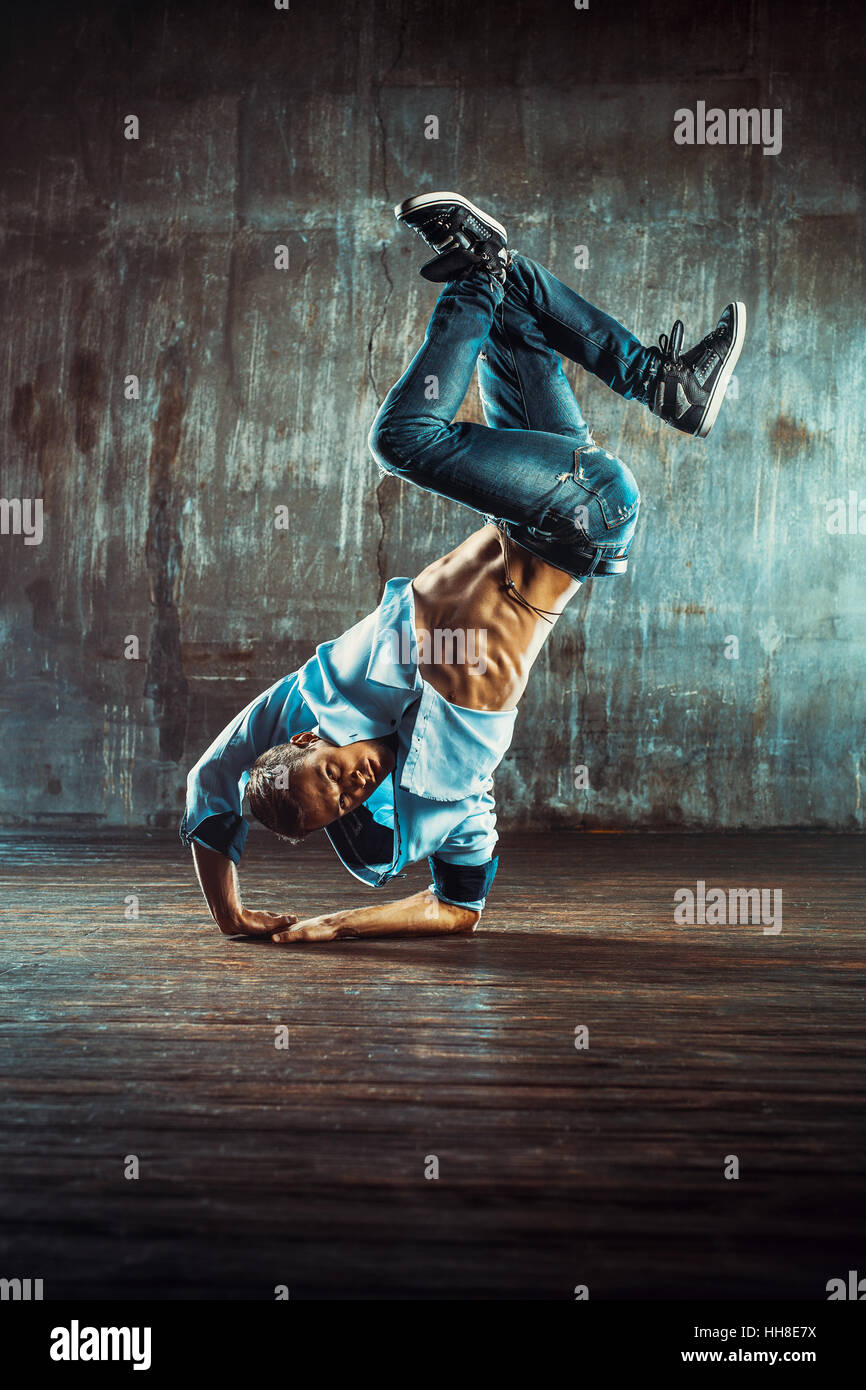 Young man break dancing on old wall background. Vintage film style colors. Stock Photo