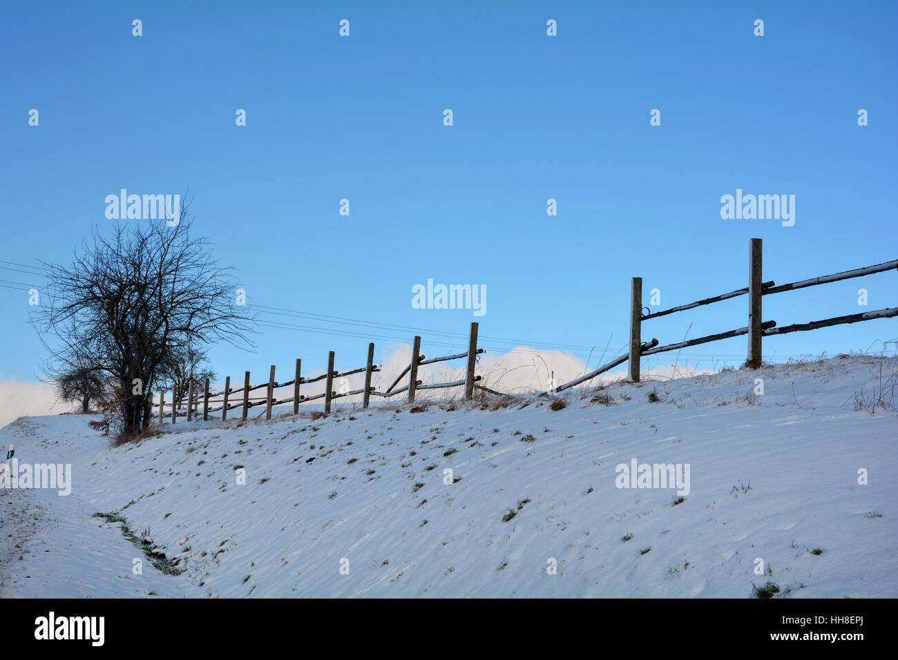 Wooden fence in winter with snow and blue sky, tree on the left Stock ...