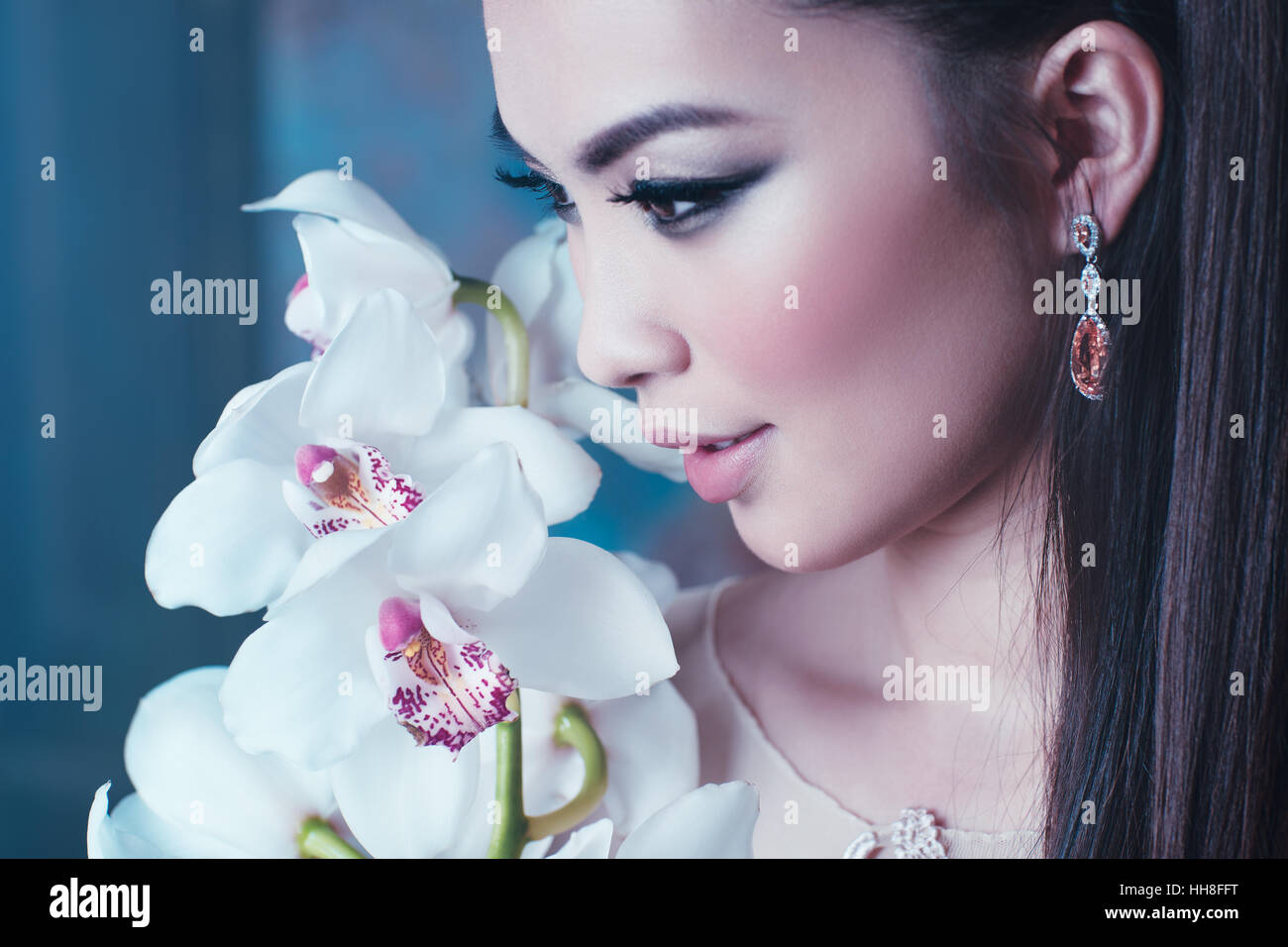 Young asian woman with orchid flower portrait close-up. Focus on lips. Stock Photo