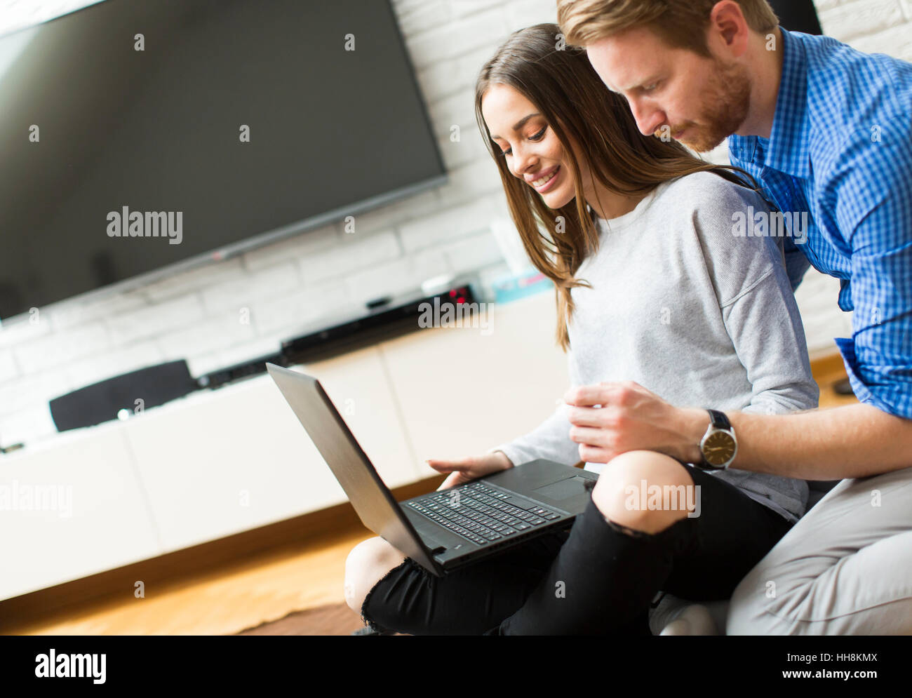 Young couple sitting while using a laptop Stock Photo - Alamy