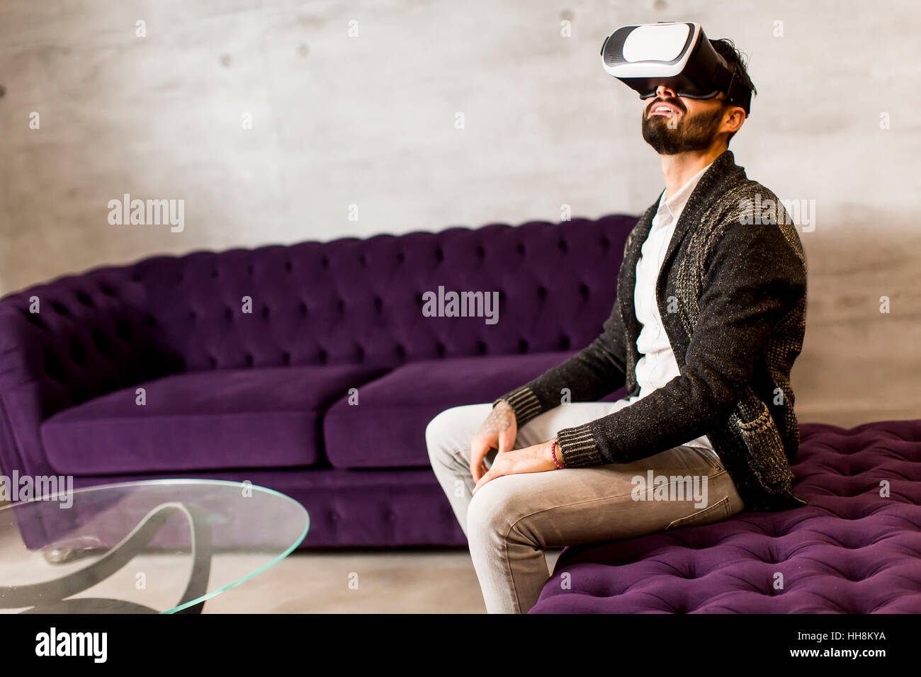 Bearded young man wearing virtual reality goggles in modern room Stock ...