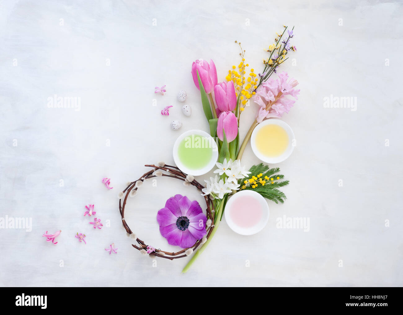 pussy willow wreath with colourful spring flowers laid out on white and gray painted backdrop Stock Photo