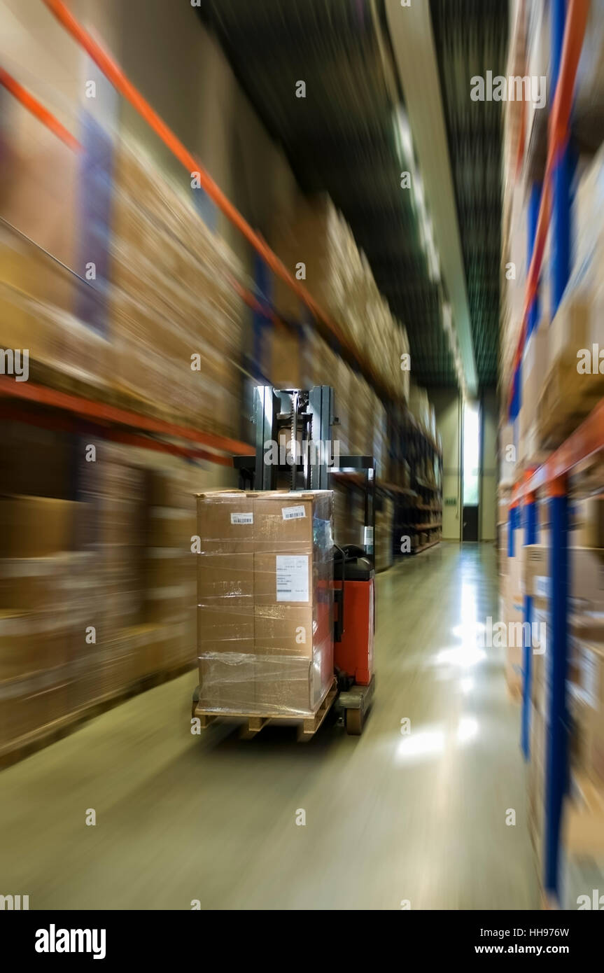 forklift with pallet moving at high speed between the pallet racks in the warehouse Stock Photo