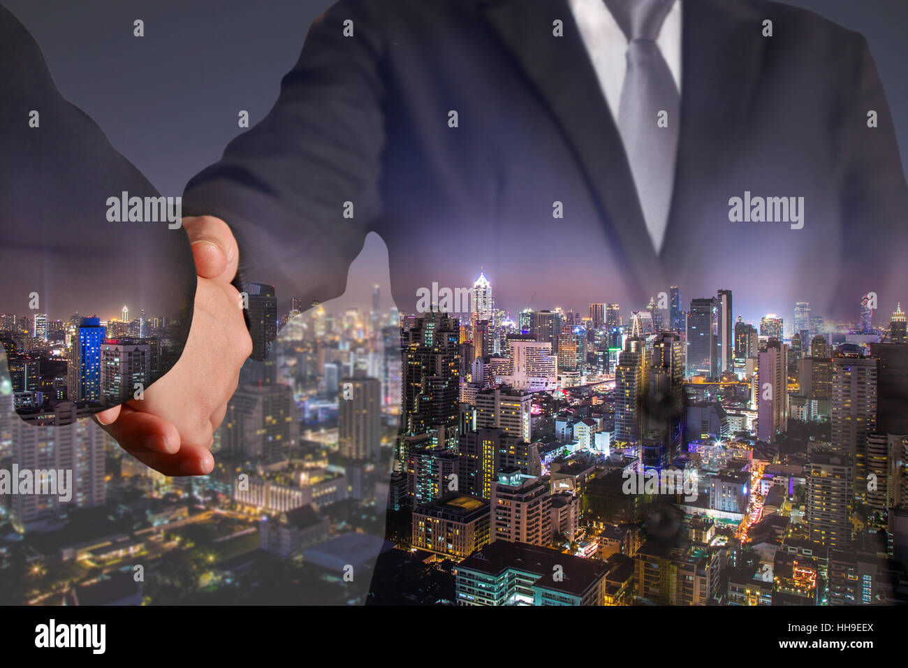 Double exposure of handshake and cityscape in the night Stock Photo