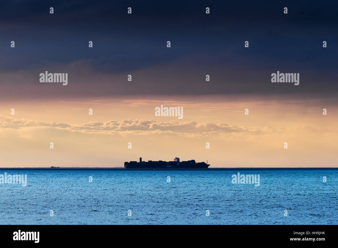 Silhouette of APL American President Lines container ship crossing Baltic sea under dramatic dark cloud formation. Poland. Stock Photo