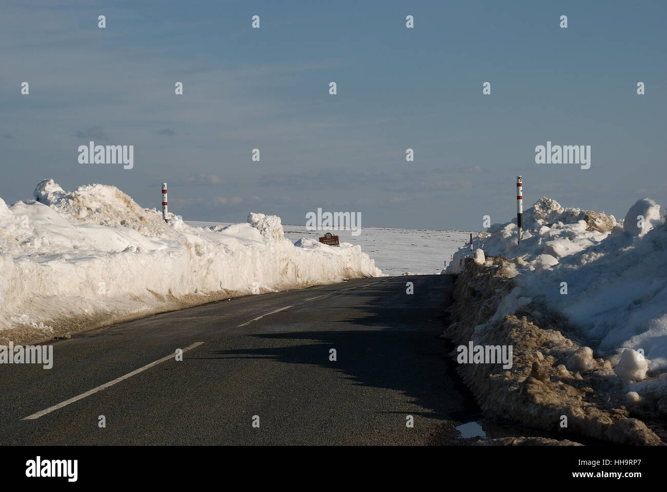 Snow cleared road on the Weardale Teesdale border with snow piled high on either side of the road Stock Photo