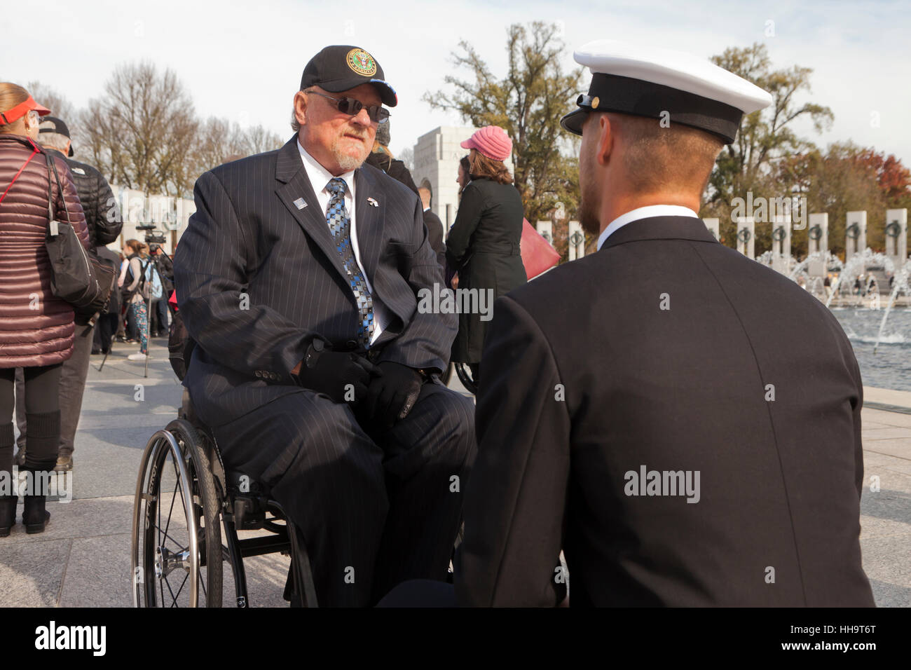 Wheelchair bound senior veteran speaking with young service member on