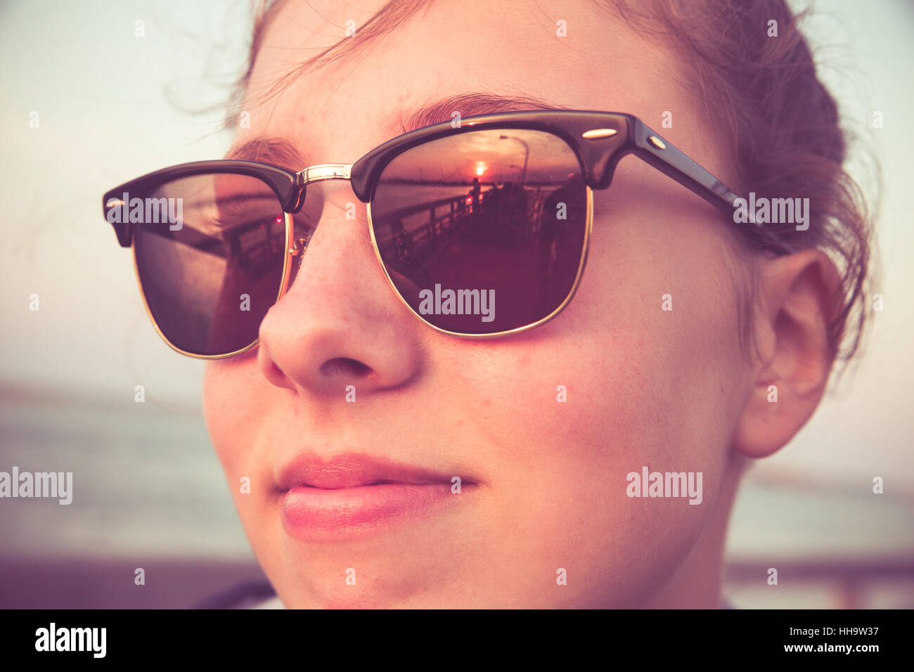 Cute teenage girl with sunset reflections in sunglasses. Image has a