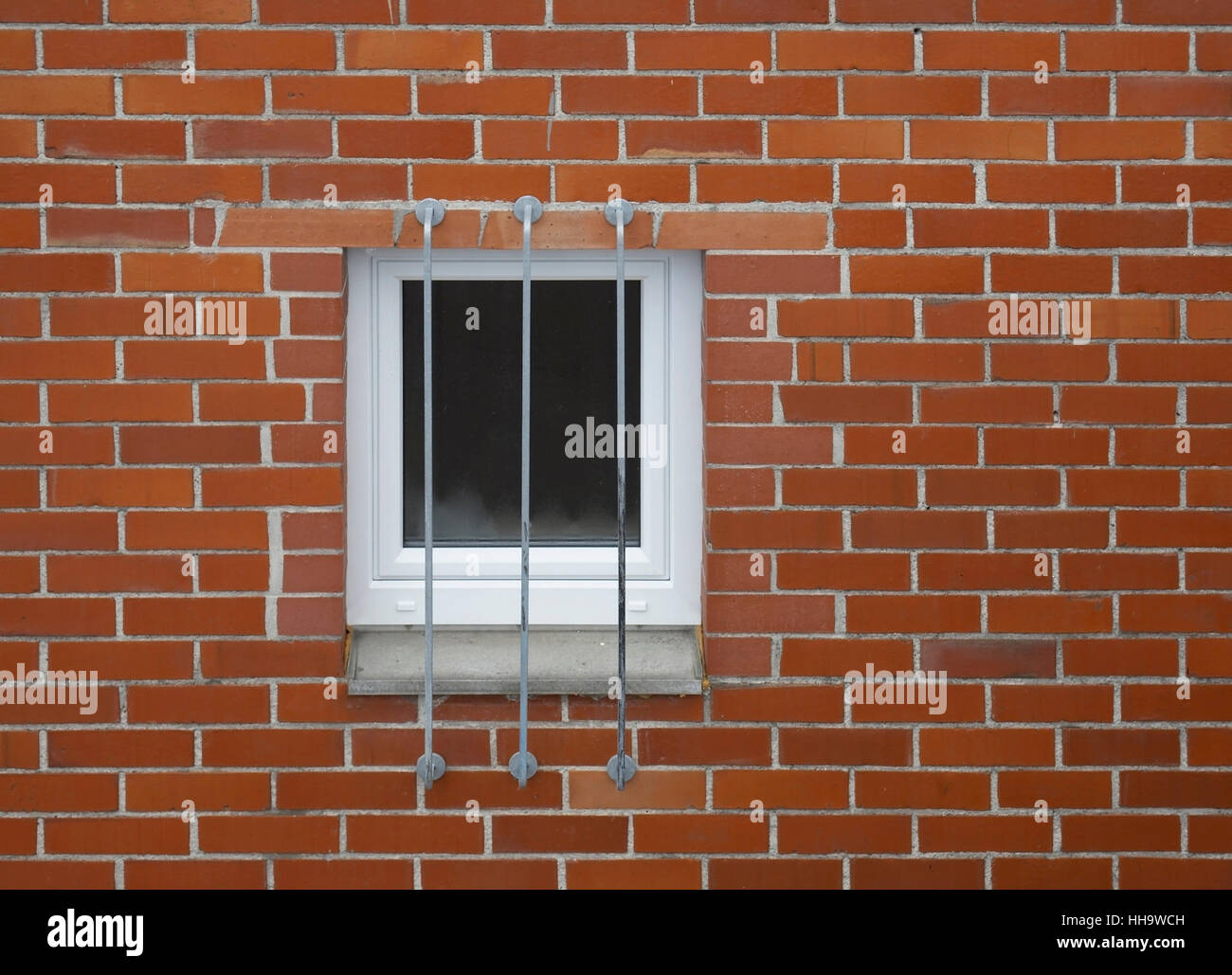 architectural detail of a barred window in a red brick wall Stock Photo