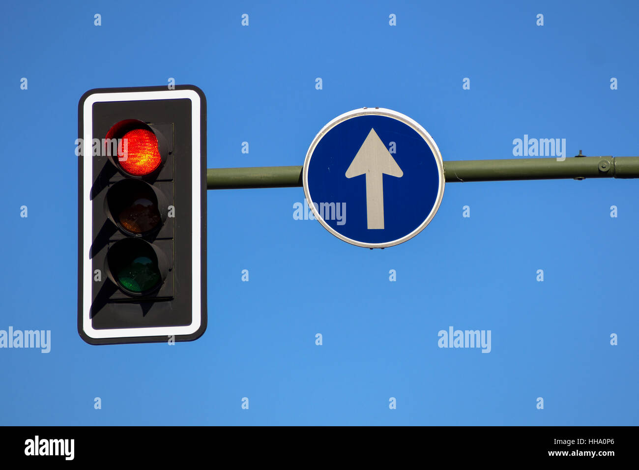 Traffic light in red and direction sign on blue sky background Stock Photo