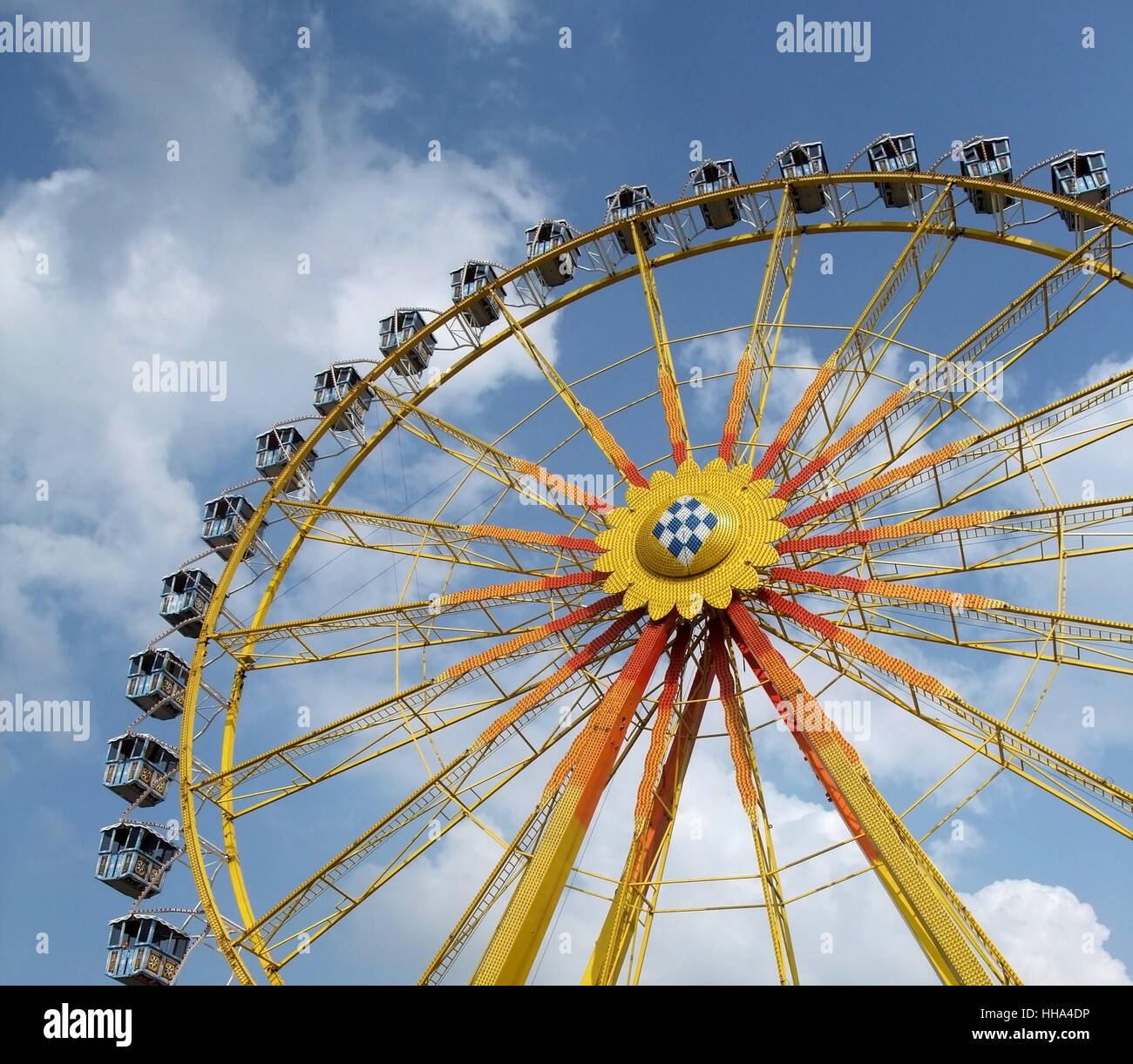 low angle detail of a big wheel in front of blue sky with some clouds Stock Photo