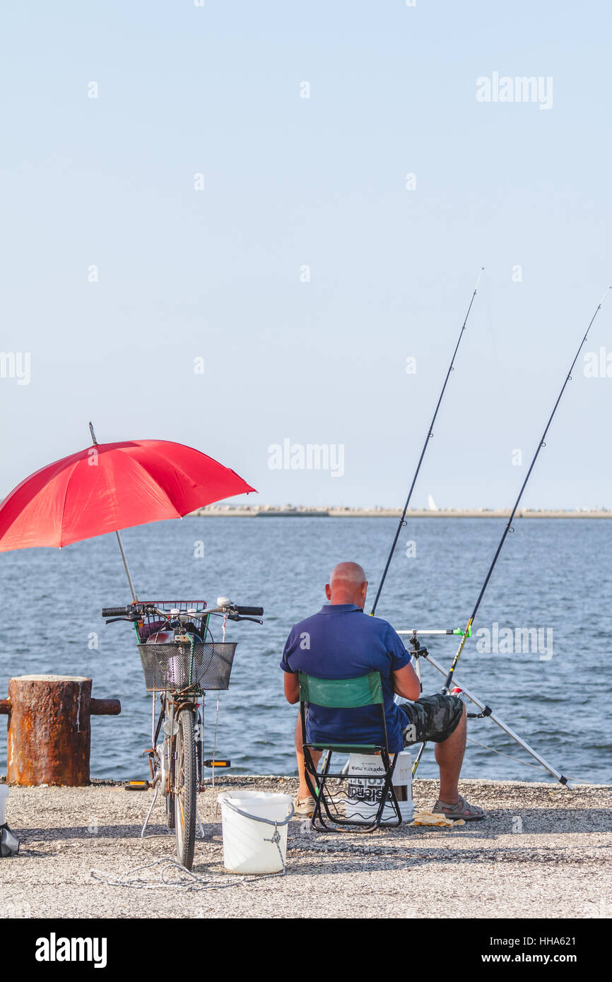 Old man with bicycle and red umbrella fishing from the pier or fishing  wharf with fishing rod in Adriatic sea in Italy Stock Photo - Alamy