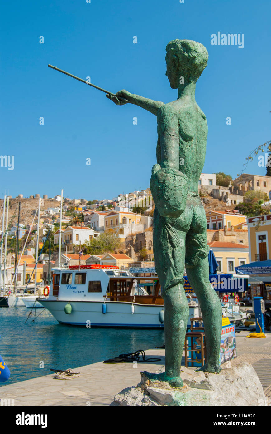 Statue of a young boy overlooking the harbour of Symi greece Stock ...