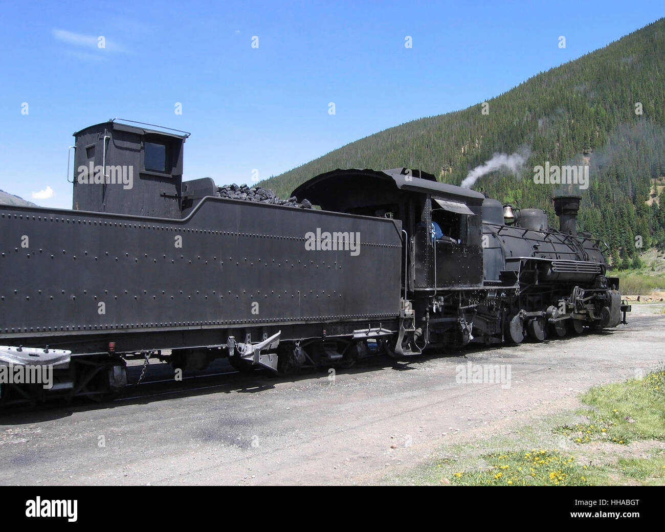 driving past dark steam engine in the Rocky Mountains at summer time Stock Photo