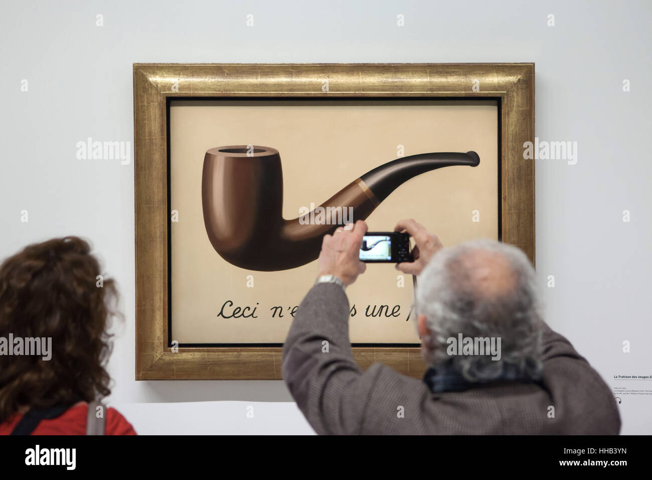 Visitor uses his smartphone to photograph the painting 'La trahison des images' ('The Treachery of Images') by Belgian surrealist artist Rene Magritte (1929) displayed at his retrospective exhibition in the Centre Pompidou in Paris, France. The French inscription 'Ceci n'est pas une pipe' means 'This is not a pipe'. The exhibition entitled 'Rene Magritte. The Treachery of Images' runs till 23 January 2017. After that the reformulated version of the exhibition will be presented at the Schirn Kunsthalle in Frankfurt am Main, Germany, from 10 February to 5 June 2017. Stock Photo