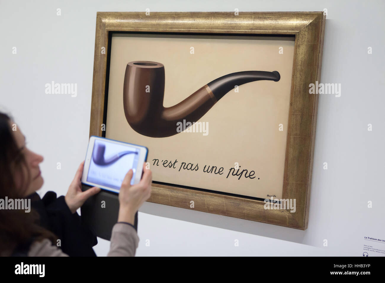 Visitor uses her tablet to photograph the painting 'La trahison des images' ('The Treachery of Images') by Belgian surrealist artist Rene Magritte (1929) displayed at his retrospective exhibition in the Centre Pompidou in Paris, France. The French inscription 'Ceci n'est pas une pipe' means 'This is not a pipe'. The exhibition entitled 'Rene Magritte. The Treachery of Images' runs till 23 January 2017. After that the reformulated version of the exhibition will be presented at the Schirn Kunsthalle in Frankfurt am Main, Germany, from 10 February to 5 June 2017. Stock Photo