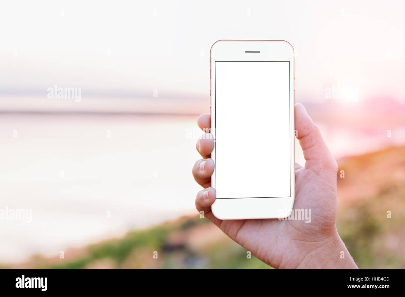 close-up hand holding phone mobile showing screen at outdoor during sunset time, mock-up new modern smartphone Stock Photo
