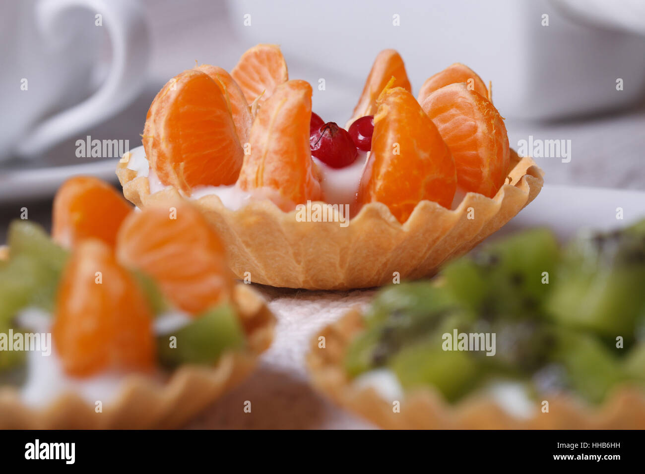 fruit tartlets with kiwi and mandarin and coffee on the table closeup
