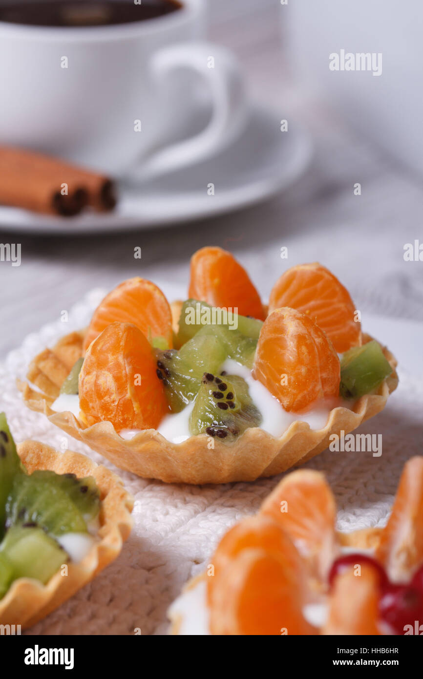 dessert fruit tartlets with mandarin, kiwi and coffee on the table