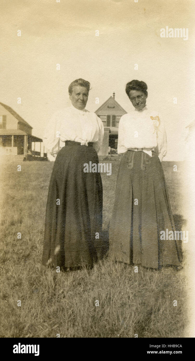 Antique 1908 photograph, two older women in front of beach cottages. Location: New England, USA. SOURCE: ORIGINAL PHOTOGRAPHIC PRINT. Stock Photo