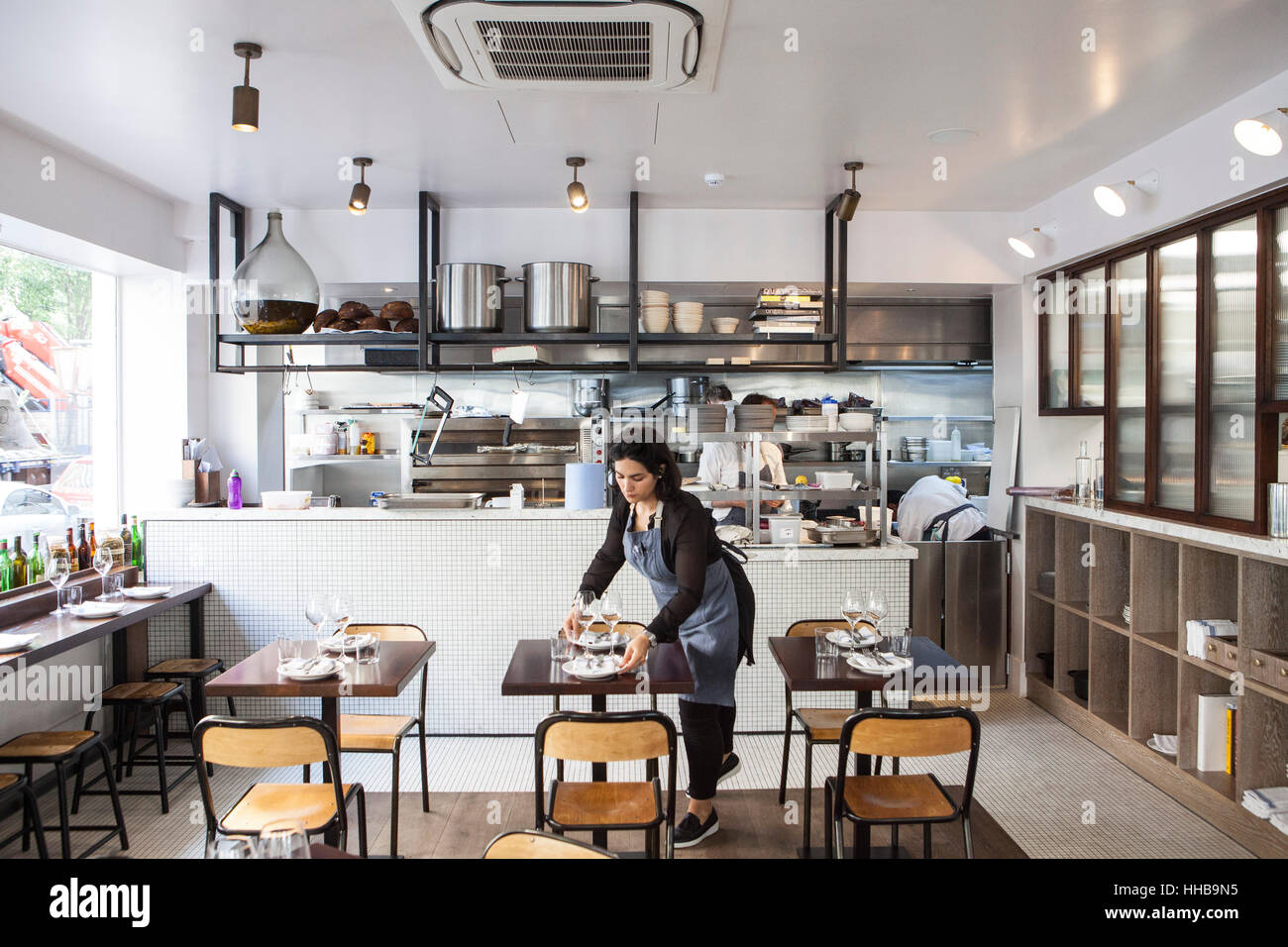 A waitress prepares the tables in the restaurant for a day's service in