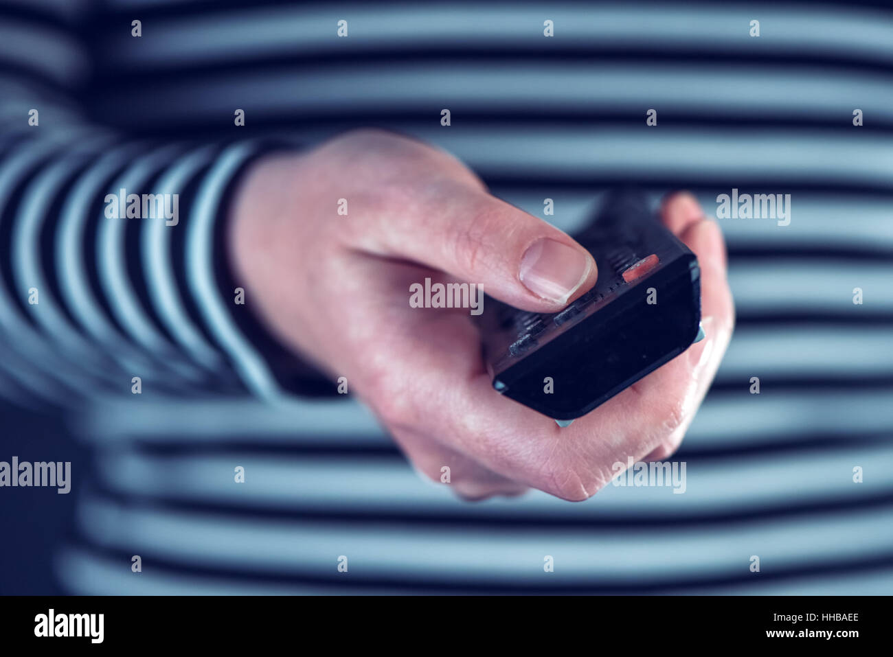 Female hand with television remote control pointing to tv set and ...