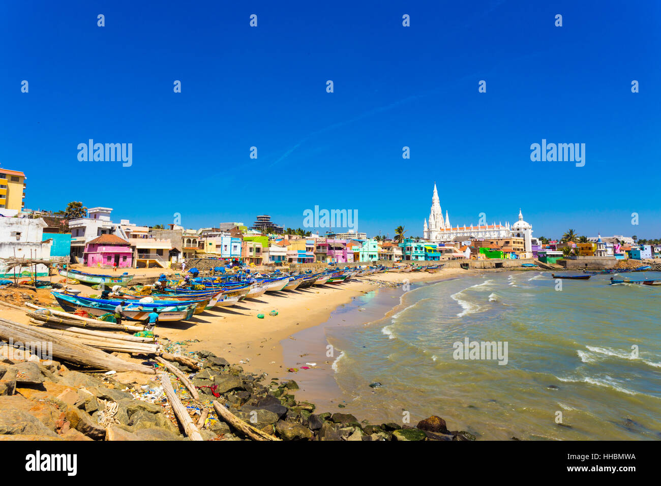 Our Lady of Ransom Shrine Church behind colorful houses on a sand beach occupied by fishing boats in Tamil Nadu. Horizontal Stock Photo